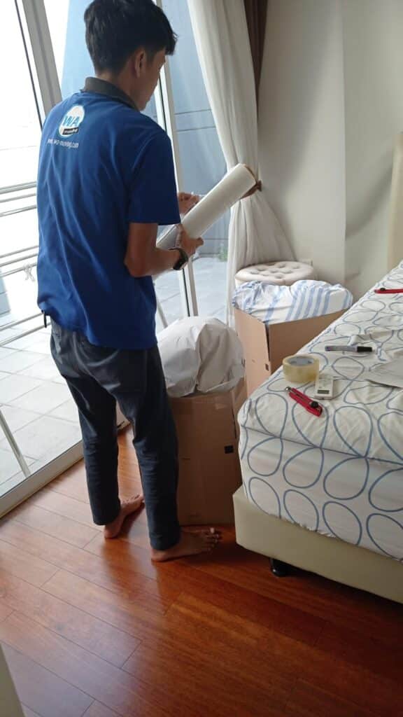 kru WA Moving sedang mengepak barang-barang di kamar tidur